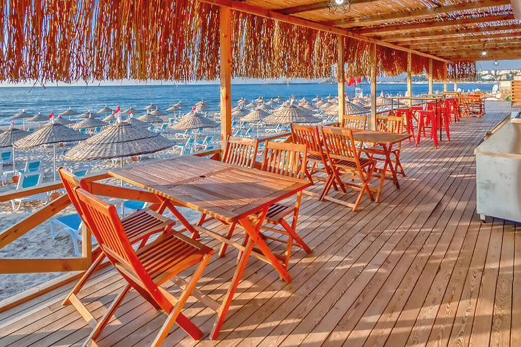 Colorful beach umbrellas and sunbeds near the pool on Sile Beach, with a scenic view of the coastline.