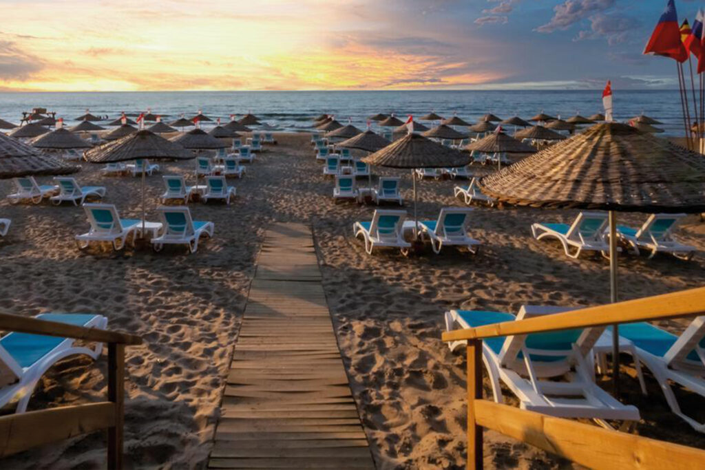 Colorful beach umbrellas and sunbeds near the pool on Sile Beach, with a scenic view of the coastline.