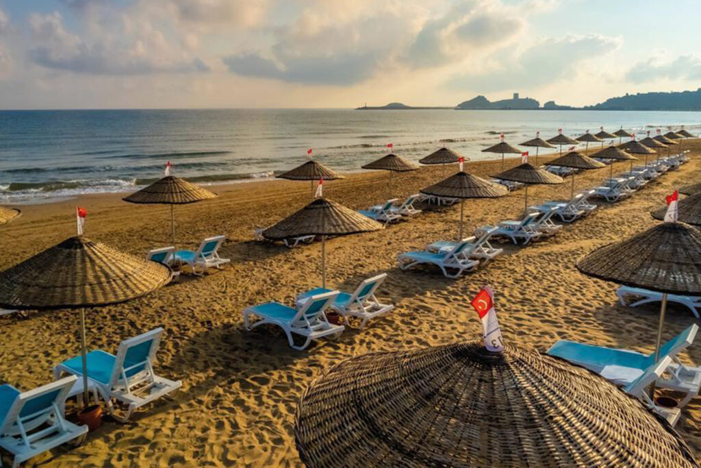 Colorful beach umbrellas and sunbeds near the pool on Sile Beach, with a scenic view of the coastline.